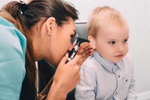 ENT doctor doing an ear exam with otoscope to little boy