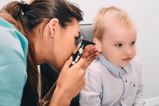 ENT doctor doing an ear exam with otoscope to little boy